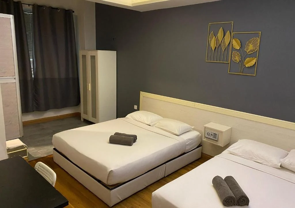 A double bed and a single bed made up with rolled towels in the family room at Travelogue Guesthouse