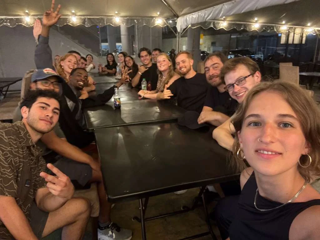 Travelogue Guesthouse guests sitting along one long table together at night in Kuala Lumpur